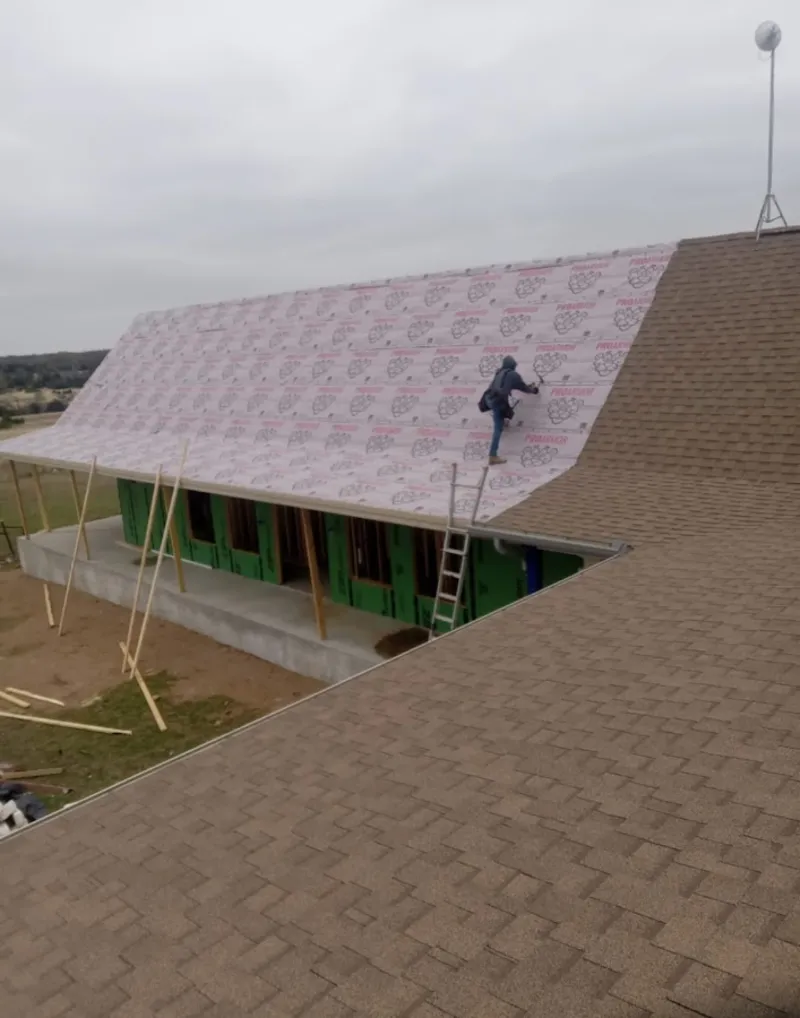 Worker preparing underlayment for a metal roof installation in Swanzey
